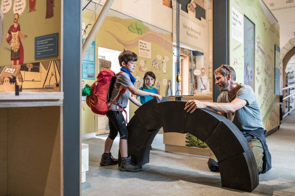 Hadrian's Wall Guide. A family of three builds a model archway.