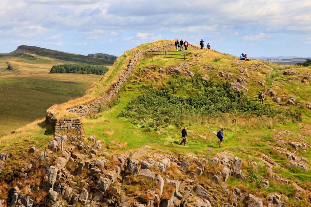 Hadrian's Wall Guide. Ramblers exploring rolling hills.