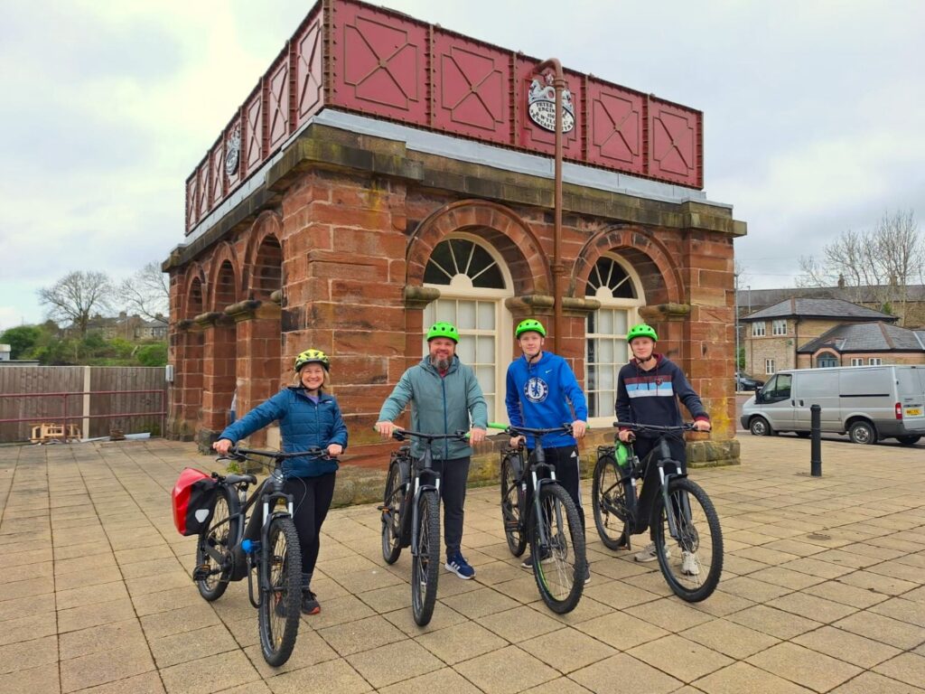 Hadrian's Wall Guide. Four cyclists wearing neon green helmets.