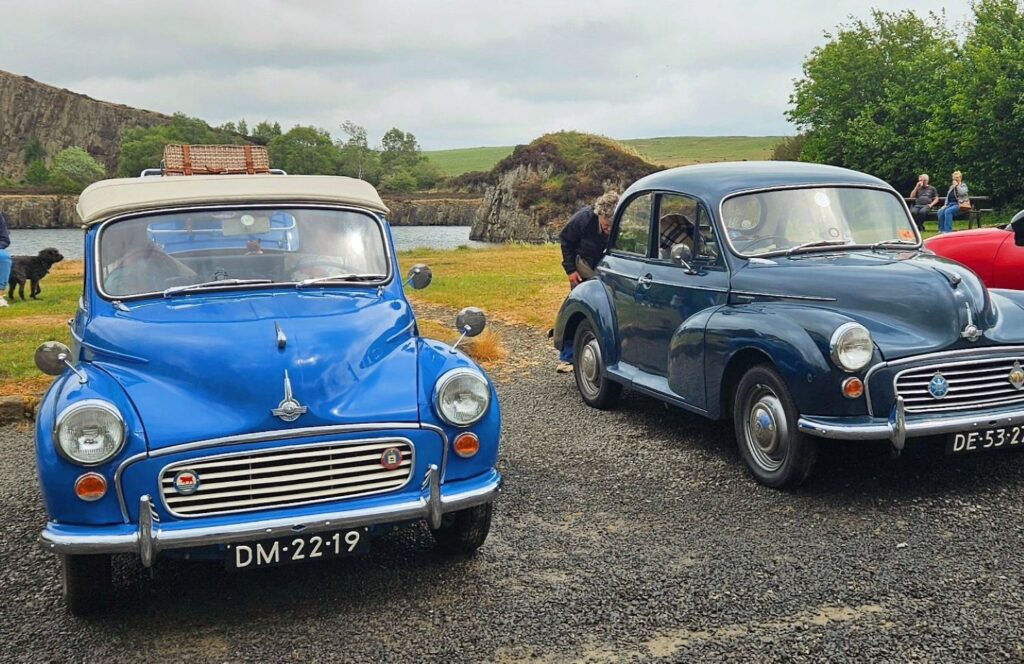 Visiting Hadrian's Wall by car. Vintage cars parked in front of a lake.