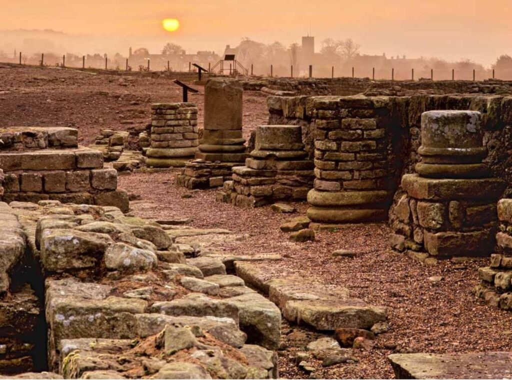 Hadrian's Wall Guide. Ruined Roman columns with a misty backdrop.